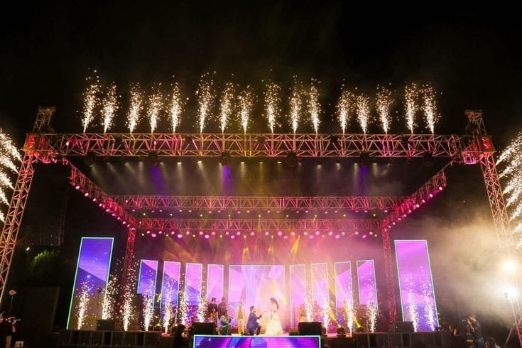 Concert stage lit pink and purple with pyrotechnic sparks