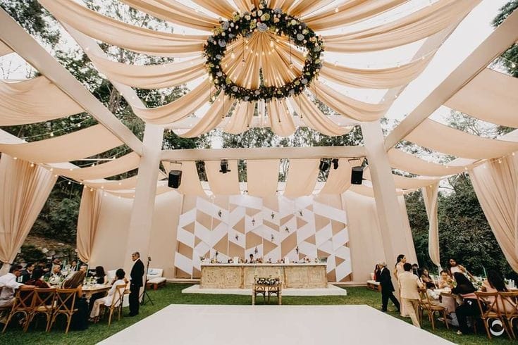 Outdoor reception under gold chandeliers at golden hour