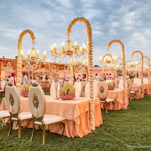 Coral draped pergola ceremony with floor cushion seating
