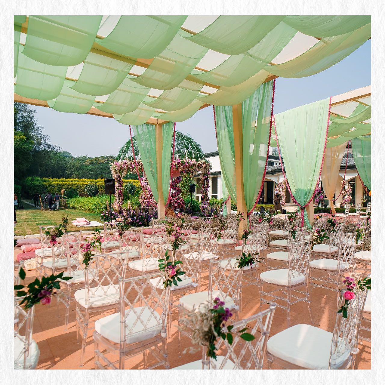 Mint green draped pergola ceremony aisle with clear chiavari chairs
